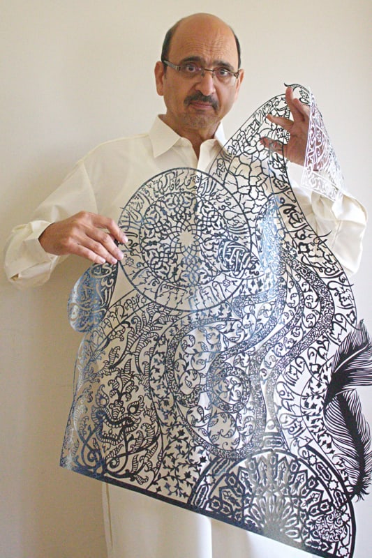 Tusif Ahmad holding a large Islamic paper-cutting artwork